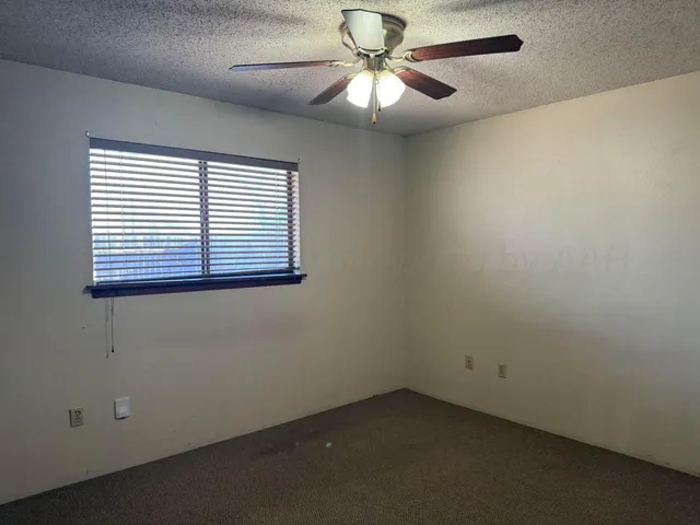 an empty room with a window and a fan