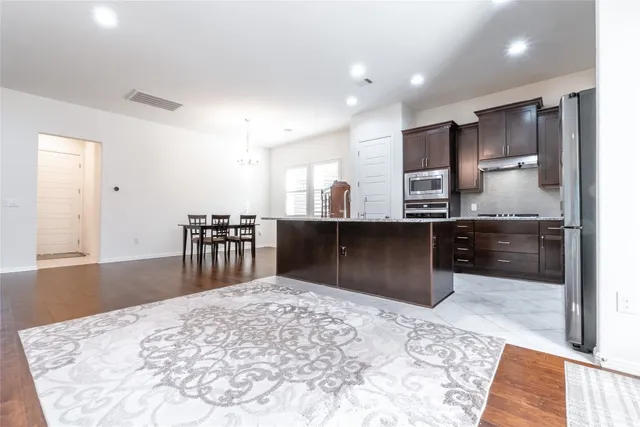 a kitchen with stainless steel appliances kitchen island granite countertop a refrigerator and a sink