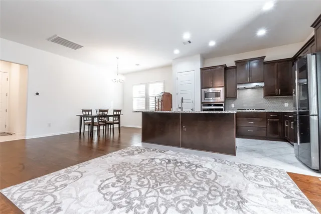 a kitchen with stainless steel appliances kitchen island granite countertop a refrigerator and a stove top oven