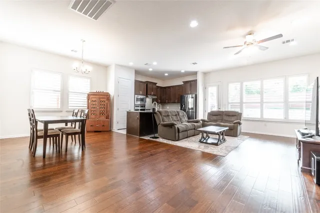 a living room with furniture and kitchen view with wooden floor