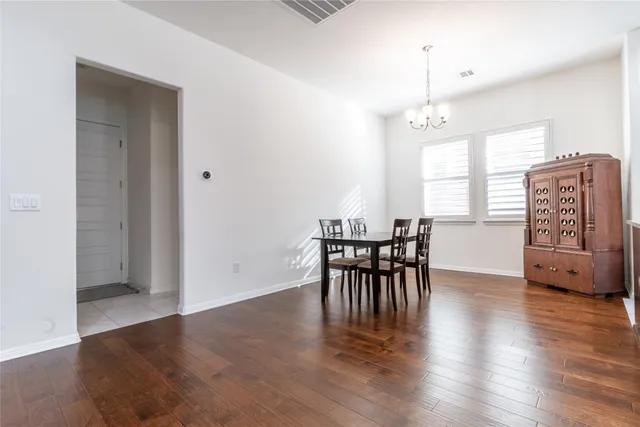 an open kitchen with granite countertop wooden floor dining table and stainless steel appliances