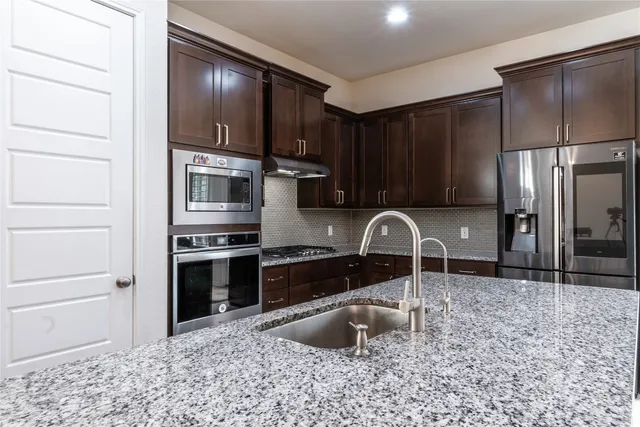 a kitchen with stainless steel appliances granite countertop a stove sink and cabinets