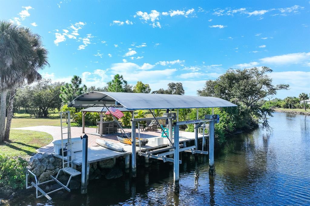 3700 Como Street Port Charlotte, FL 33948 - Photo 86 of 88 a view of a patio with lawn chairs under an umbrella with palm trees