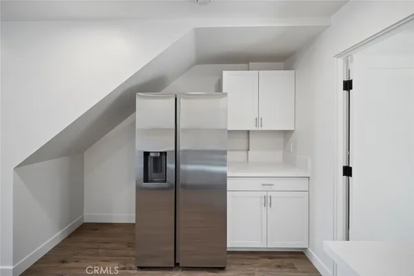 a view of a refrigerator in kitchen and an empty room