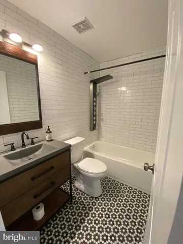 a bathroom with a sink a toilet a mirror a bathtub and shower