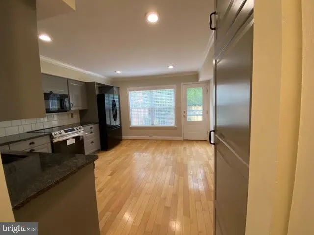 a view of a kitchen center island wooden floor and stainless steel appliances