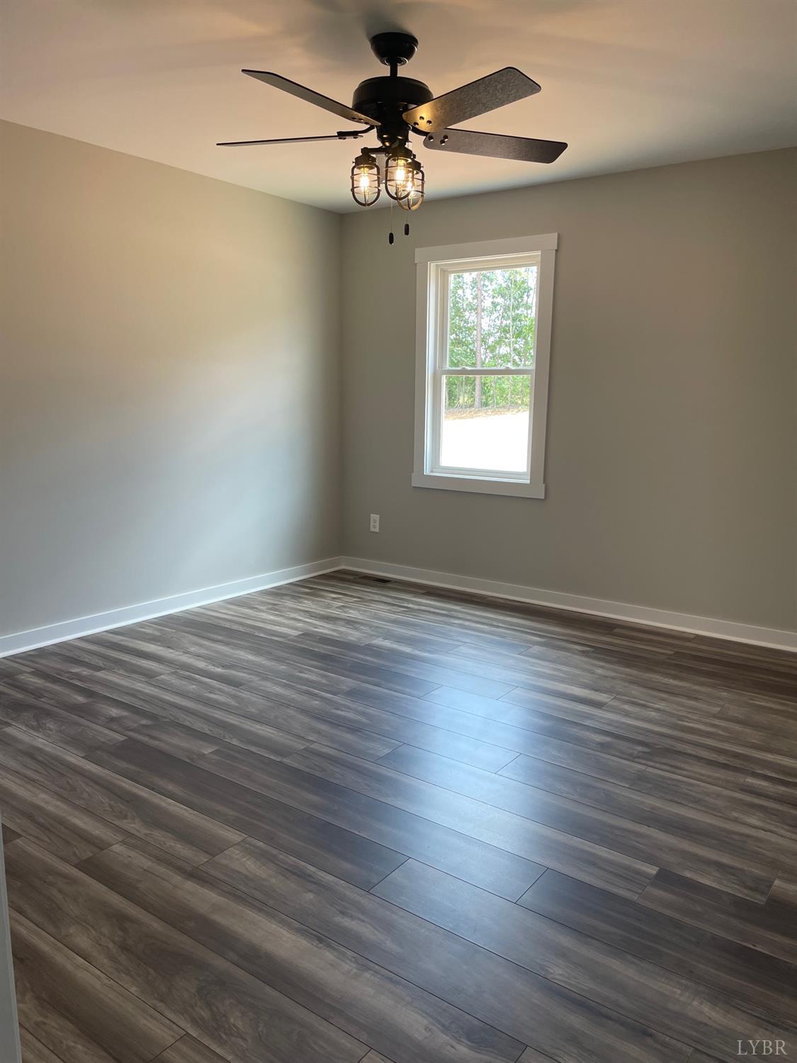 819 Winfall Road Rustburg, VA 24554 - Photo 11 of 15 an empty room with wooden floor chandelier fan and windows