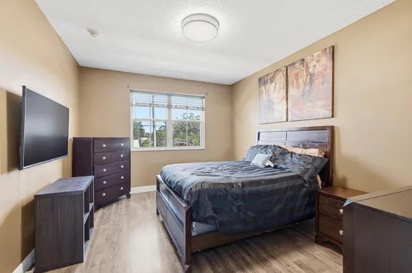 a bedroom with a bed and a flat tv screen on dresser