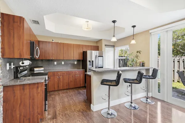 a kitchen with granite countertop wooden cabinets a stove a sink and a dining table with chairs