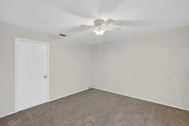 an empty room with a fan & a window