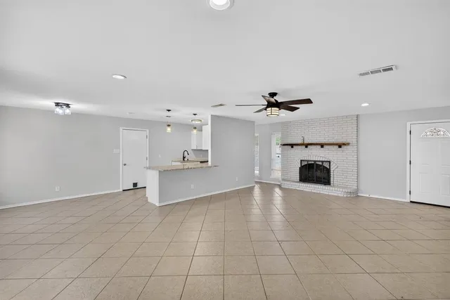 an empty room with fireplace and a chandelier fan