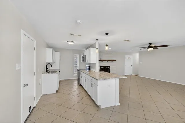 a large white kitchen with a stove a sink dishwasher and a refrigerator with white cabinets