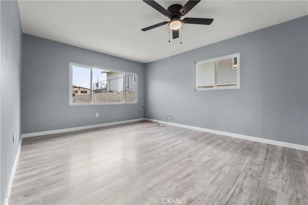 a view of empty room with wooden floor and fan