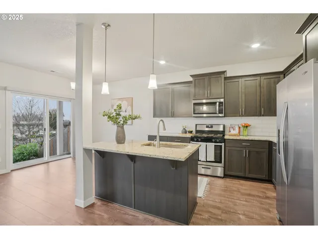 a kitchen with kitchen island granite countertop a sink stainless steel appliances and cabinets