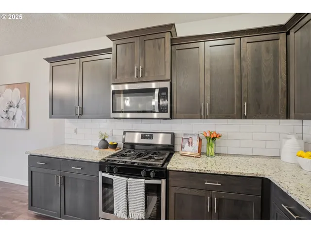 a kitchen with granite countertop a sink stove and microwave