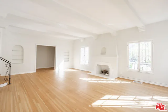 a view of a livingroom with wooden floor a fireplace and windows