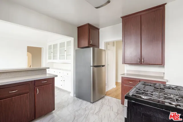 a kitchen with granite countertop wooden cabinets a refrigerator and a stove top oven