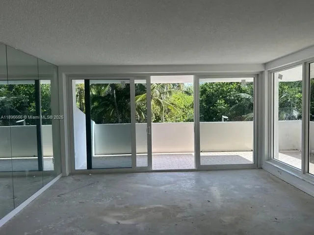 a view of an empty room with a fireplace and windows