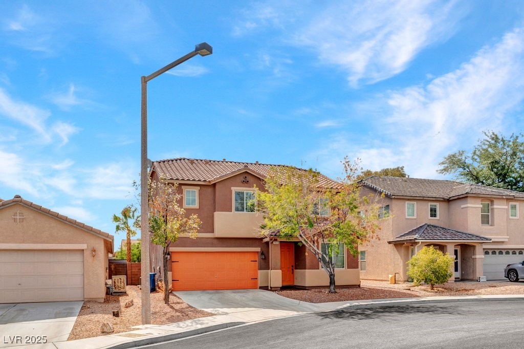 Mediterranean / spanish-style home featuring concrete driveway, stucco siding, an attached garage, and a tiled roof
