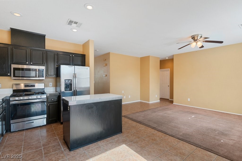 5033 Ropers Rock Court Las Vegas, NV 89131 - Photo 38 of 40 Kitchen featuring appliances with stainless steel finishes, a center island, dark cabinetry, tile countertops, and open floor plan