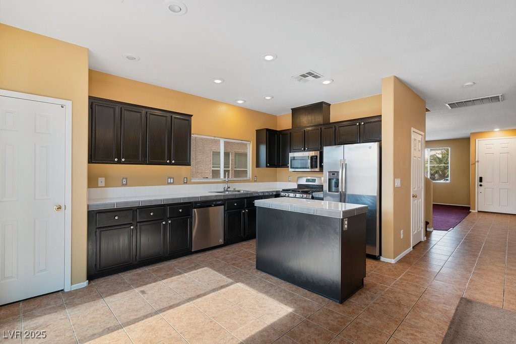 5033 Ropers Rock Court Las Vegas, NV 89131 - Photo 4 of 40 Kitchen with a center island, stainless steel appliances, recessed lighting, light tile patterned flooring, and tile countertops
