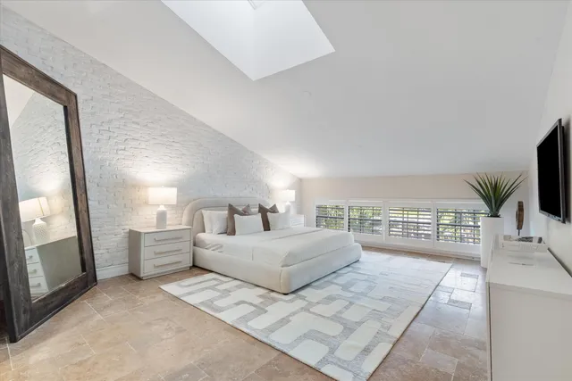 a bedroom with a large bed and a flat tv screen on dresser