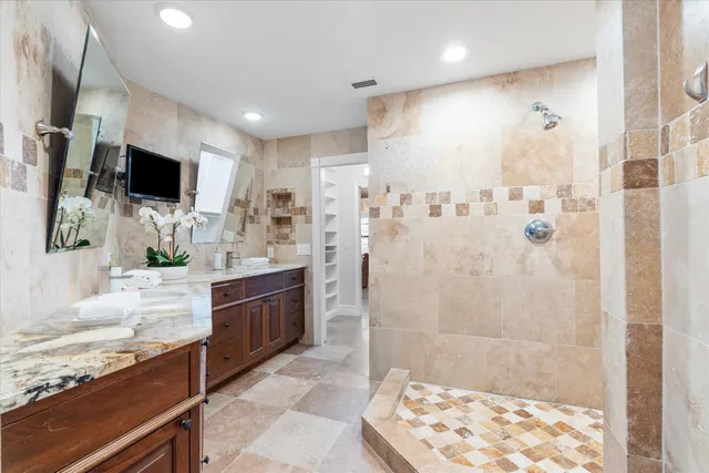 a spacious bathroom with a granite countertop sink a large mirror and shower