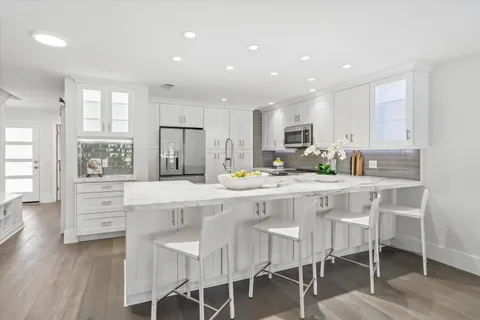 a kitchen with stainless steel appliances granite countertop a table chairs sink refrigerator and cabinets