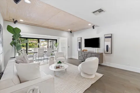 a living room with furniture a flat screen tv and a floor to ceiling window