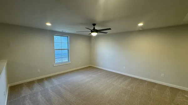 an empty room with a ceiling fan and window