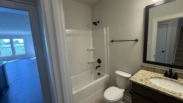 a bathroom with a granite countertop sink toilet a mirror and bathtub