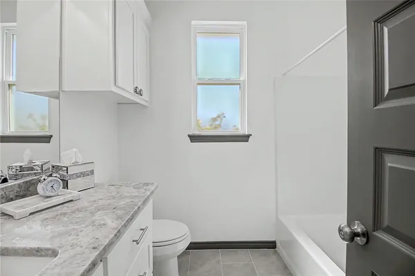a bathroom with a granite countertop sink a toilet and a mirror