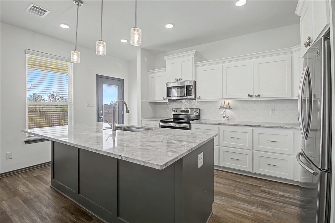 2406 Lightfoot Lane Bryan, TX 77803 - Photo 14 of 38 a kitchen with kitchen island granite countertop a sink cabinets and stainless steel appliances