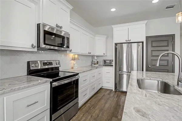 a kitchen with stainless steel appliances granite countertop a sink a stove and a microwave