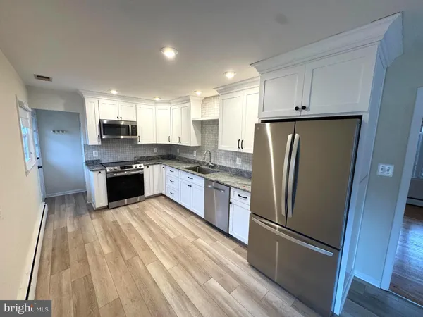 a kitchen with stainless steel appliances granite countertop a refrigerator a stove and a sink