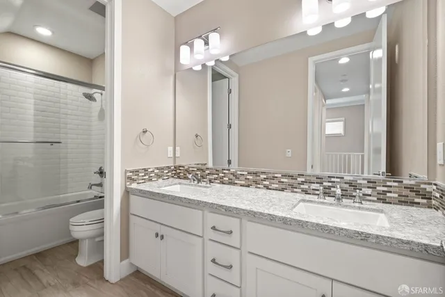 a bathroom with a granite countertop sink toilet mirror and bathtub