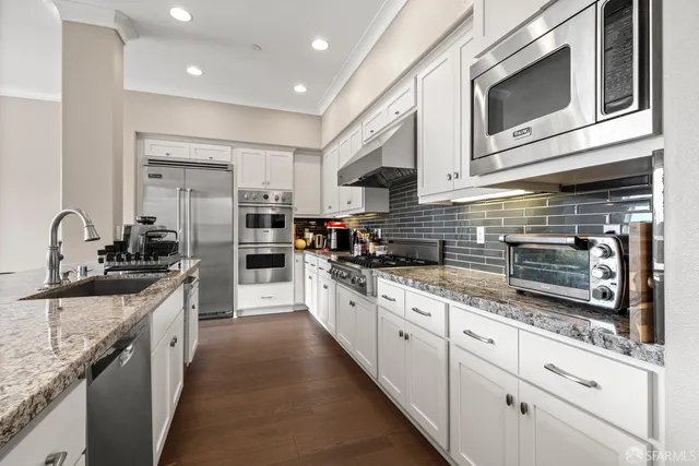 a large kitchen with stainless steel appliances granite countertop a stove and a sink