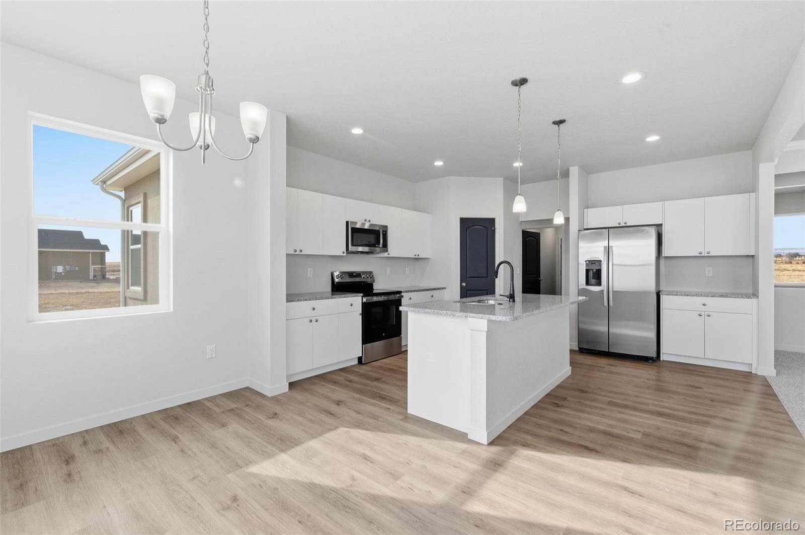 24515 Big Springs Road Peyton, CO 80831 - Photo 12 of 30 a large kitchen with kitchen island a refrigerator a stove a sink dishwasher a oven with white cabinets and wooden floor