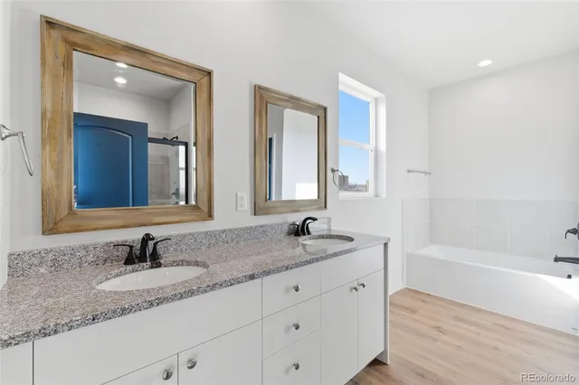 a bathroom with double vanity sinks and a bathtub