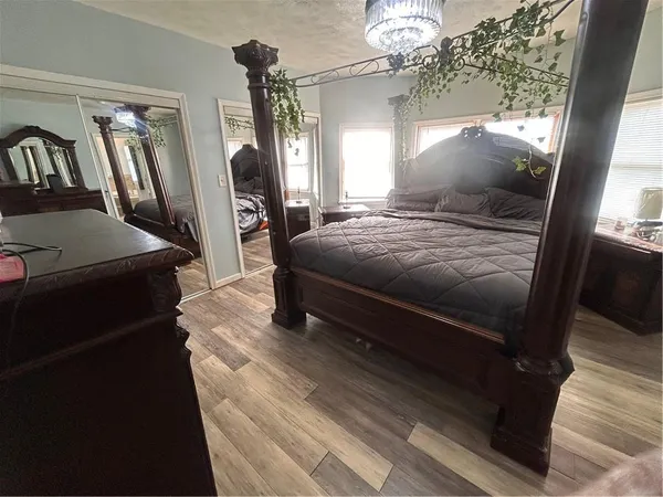 a bedroom with a bed wooden floor and flat screen tv