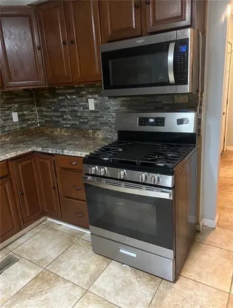 a kitchen with stainless steel appliances granite countertop a refrigerator a stove a sink a microwave and cabinets