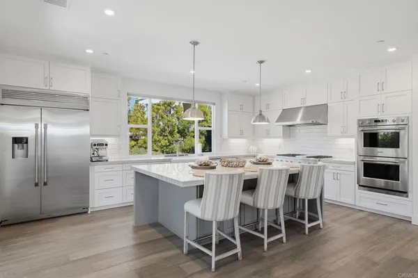 a kitchen with kitchen island granite countertop a sink a stove a refrigerator and island with wooden floor