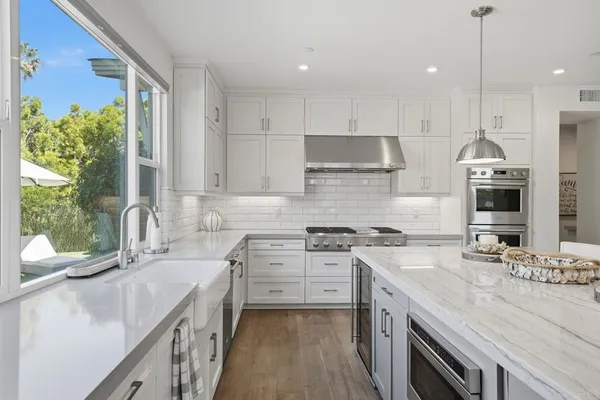 a view of a patio with couches table and chairs with plants and wooden fence