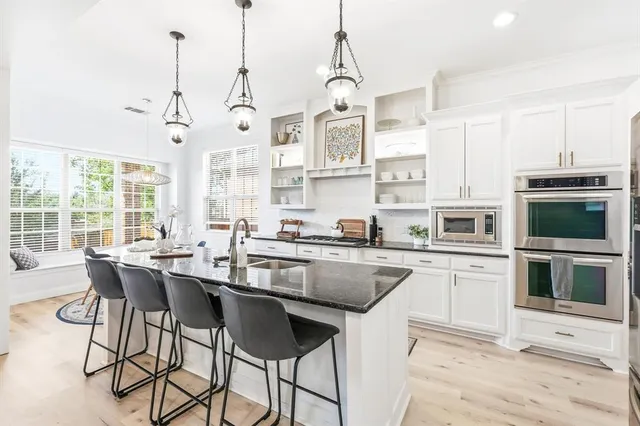 a kitchen with stainless steel appliances granite countertop a stove a sink and a microwave