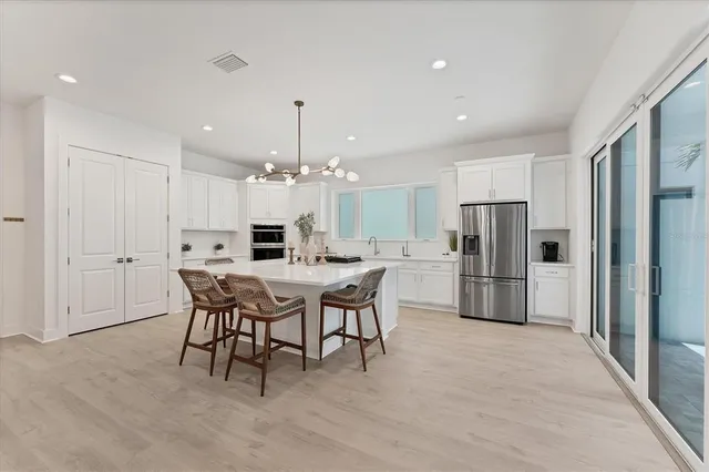 a kitchen with stainless steel appliances kitchen island hardwood floor and a refrigerator