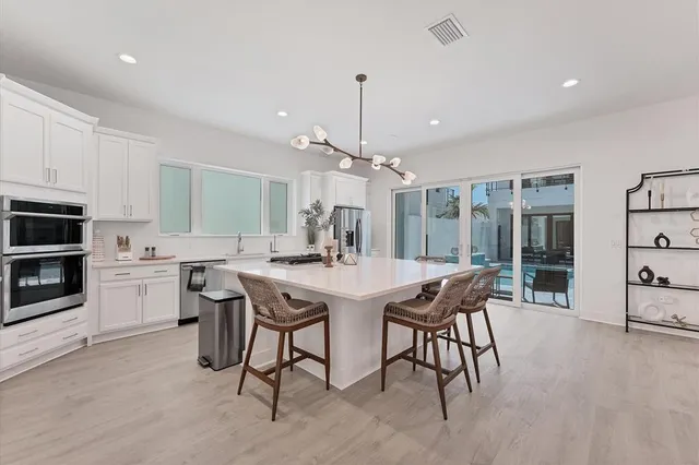 a kitchen with stainless steel appliances kitchen island granite countertop a stove a sink a dining table and chairs