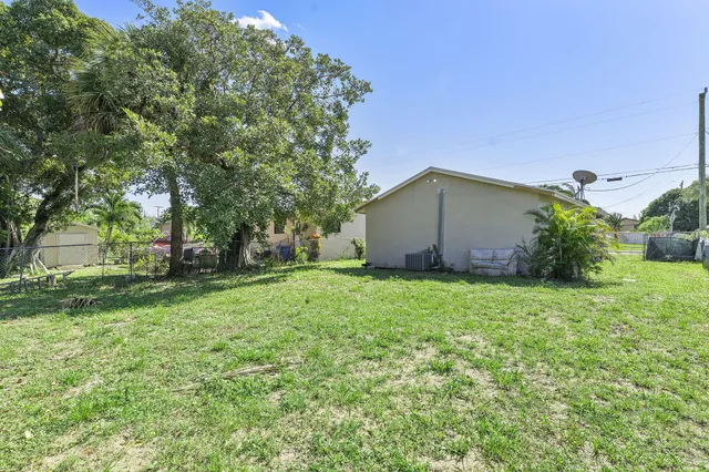 a backyard of a house with plants and large tree