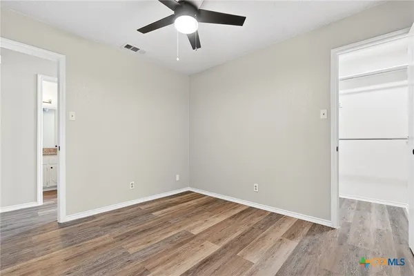 an empty room with wooden floor and windows