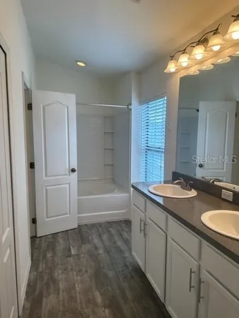 a bathroom with a granite countertop sink mirror and a bathtub