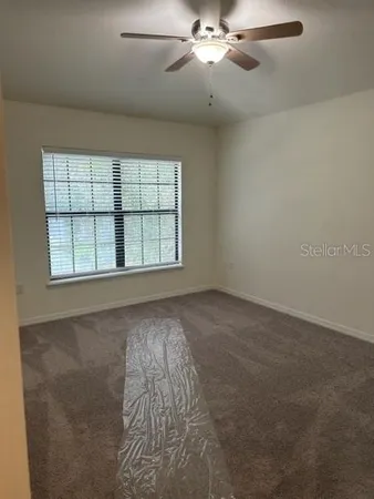 an empty room with a chandelier fan and windows